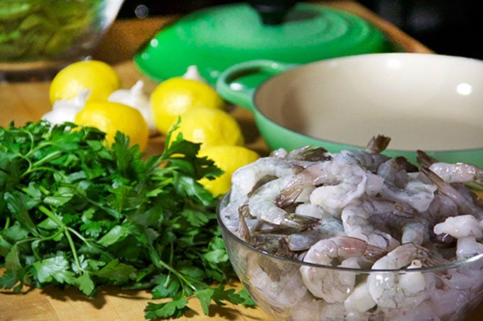 Raw shrimp in a bowl with lemons and parsley