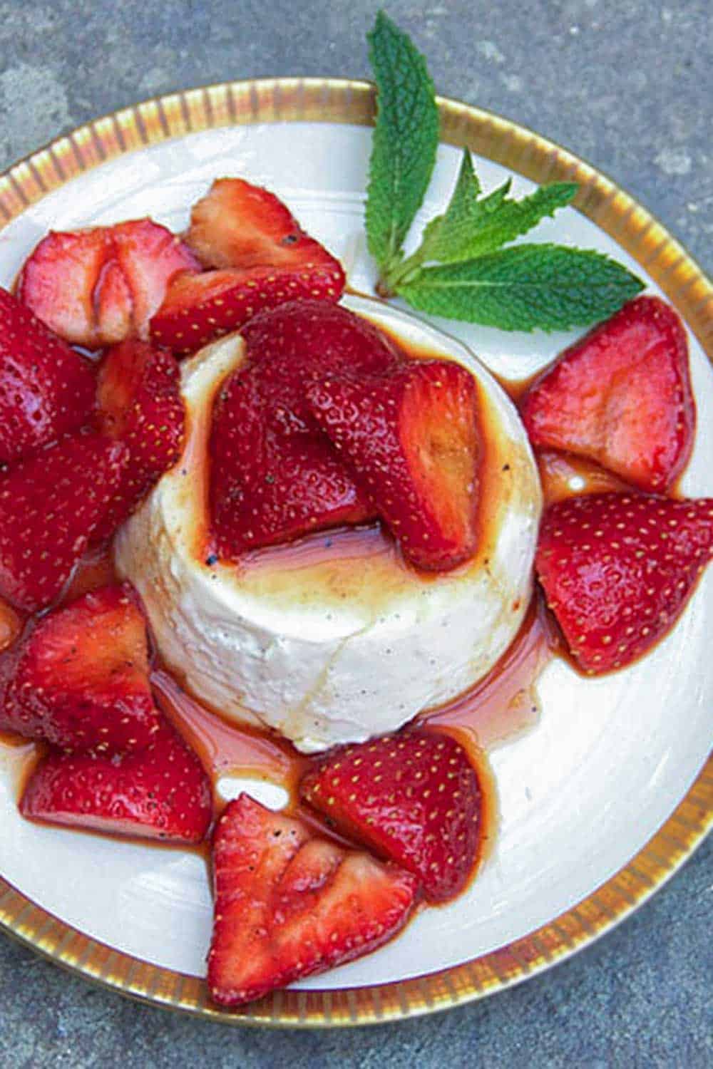 vanilla panna cotta surrounded by and topped with balsamic marinated strawberries