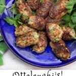 Bright blue bowl filled with oblong turkey zucchini meatballs and several sprigs of cilantro