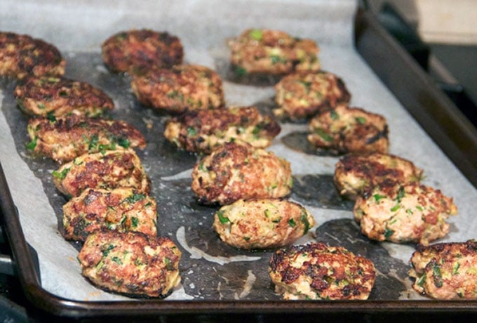 18 turkey zucchini meatballs on a parchment line baking pan