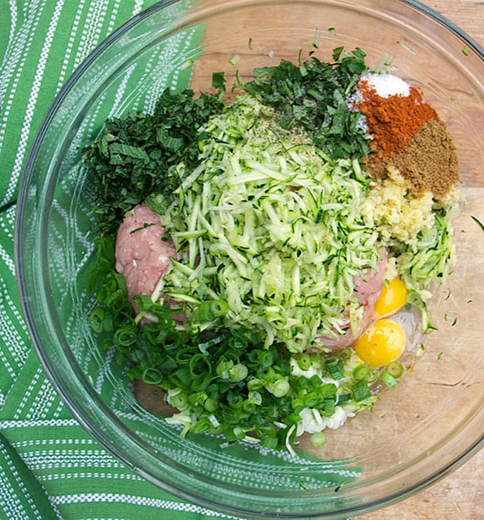 a bowl of ground turkey, shredded zucchinil, herbs, spices and an egg, ingredients for Ottolenghi's amazing Turkey Zucchini Meatballs.