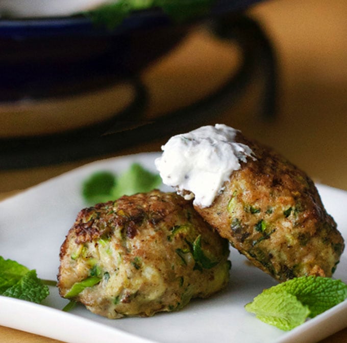 two turkey zucchini meatballs, one dipped in lemony yogurt sauce