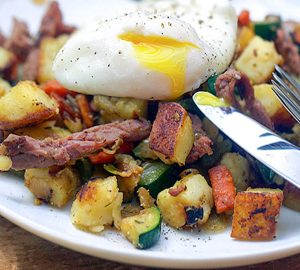 Corned beef hash with lots of veggies and a runny poached egg on top