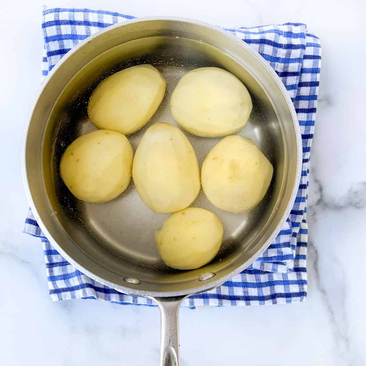6 peeled Yukon gold potatoes in a saucepan covered with water.