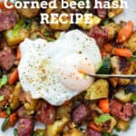 Corned beef hash with carrots, peppers and zucchini in the mix, topped with a poached egg that has a knife cutting into the yolk.