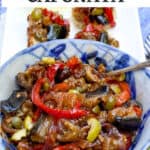 bowl of caponata showing stewed pieces of eggplant, sliced peppers, chopped olives and capers.