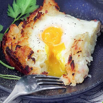 a square piece of shredded potato casserole (rosti) with a fork and some egg yolk dripping down