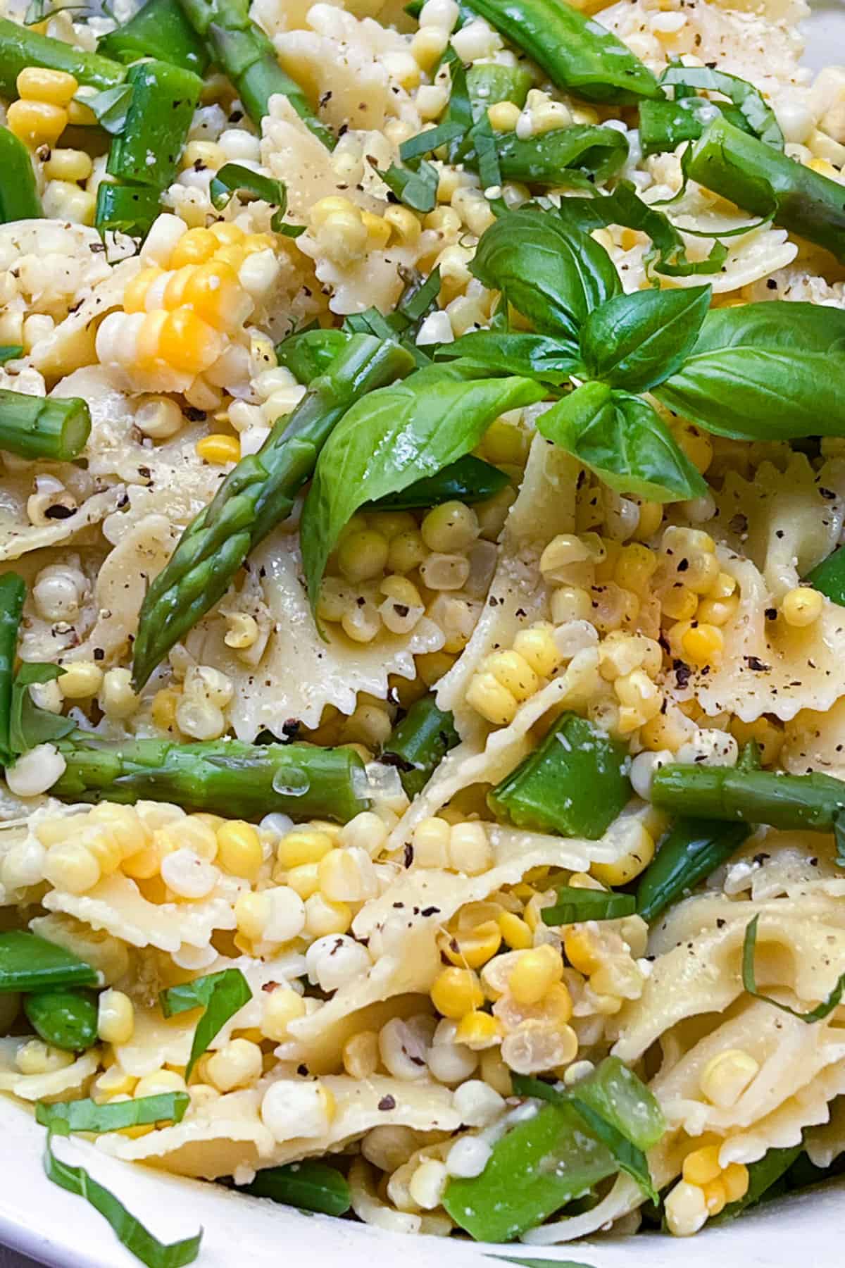 frilly pasta noodles mixed with asparagus, corn and snap peas