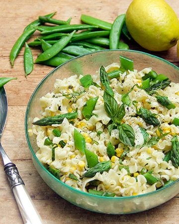 Everyone needs a great pasta primavera recipe in their repertoire. This lemony pasta is the one I love for spring and summer dinners and backyard barbecues: crisp tender asparagus, sugar snap peas and corn, mixed with frilly pasta, tossed in a luscious lemony sauce with parmesan cheese, basil and lots of fresh ground black pepper.