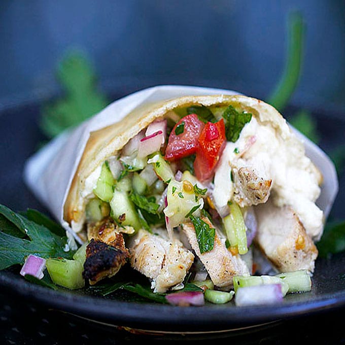 close up of a Spicy Chicken Shawarma wrap with cucumbers, tomatoes and re onion