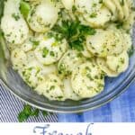 French potato salad in a glass bowl with a parsley sprig in the center