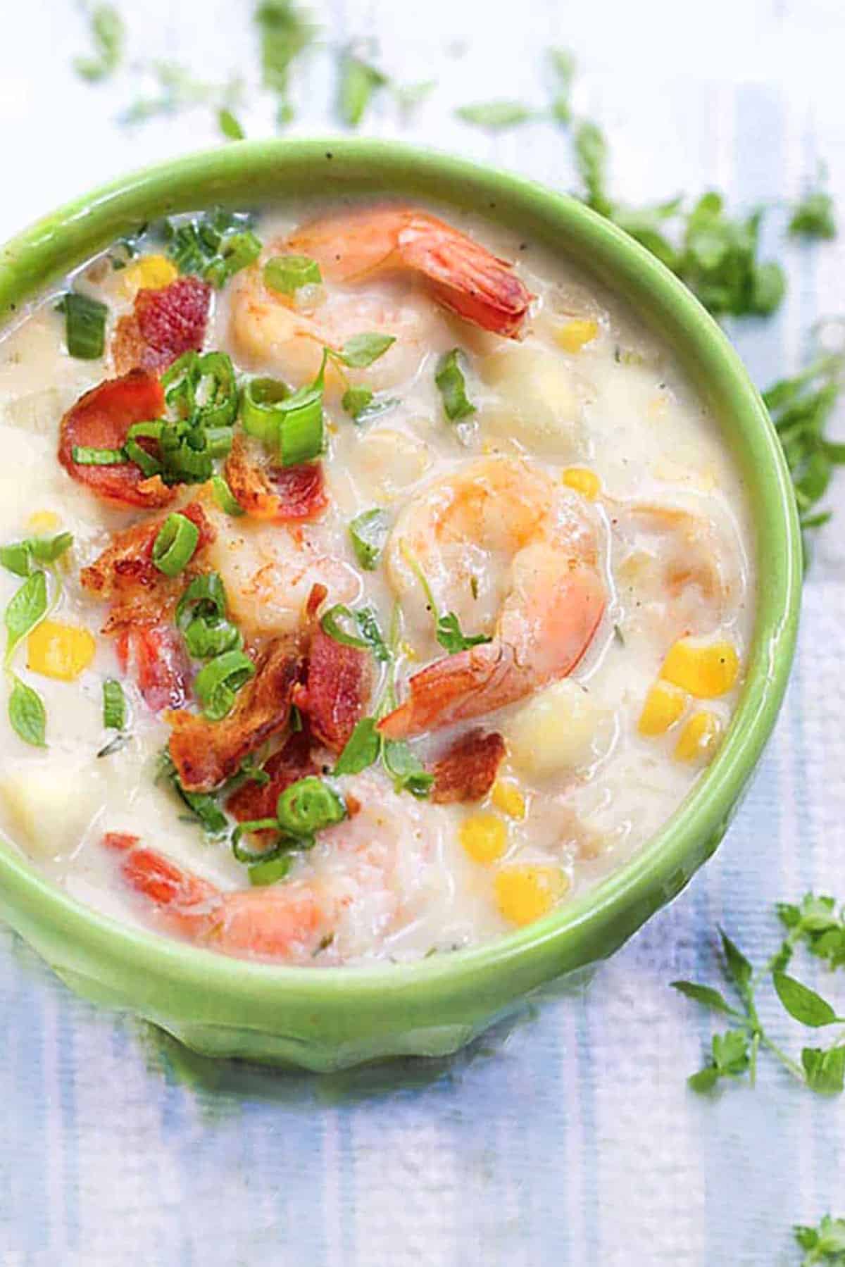 bowl of shrimp and corn chowder topped with crumbled bacon and chopped scallions