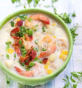 bowl of shrimp and corn chowder topped with crumbled bacon and chopped scallions