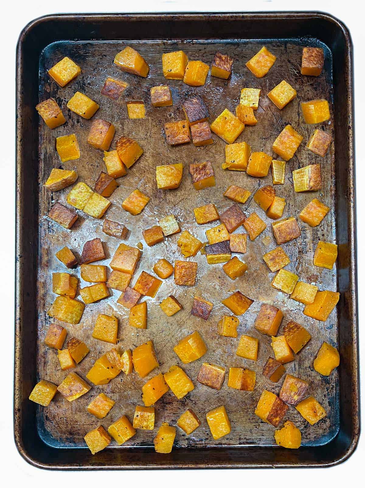 cubes of roasted butternut squash on a rimmed baking sheet