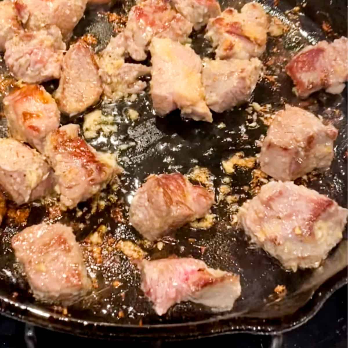 Cubes of lamb browning in a cast iron skillet