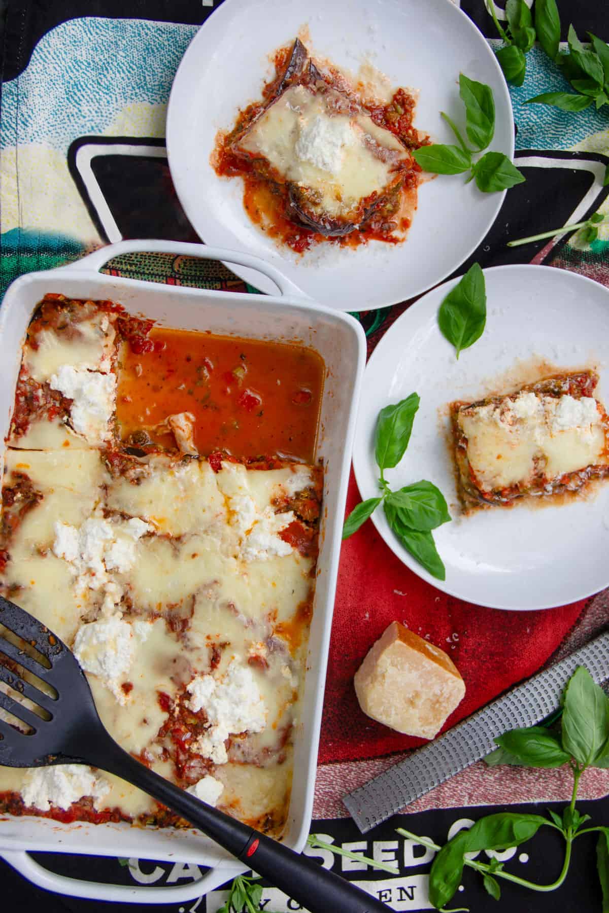 rectangular casserole filled with eggplant lasagna, two pieces have been cut out and are on two small plates