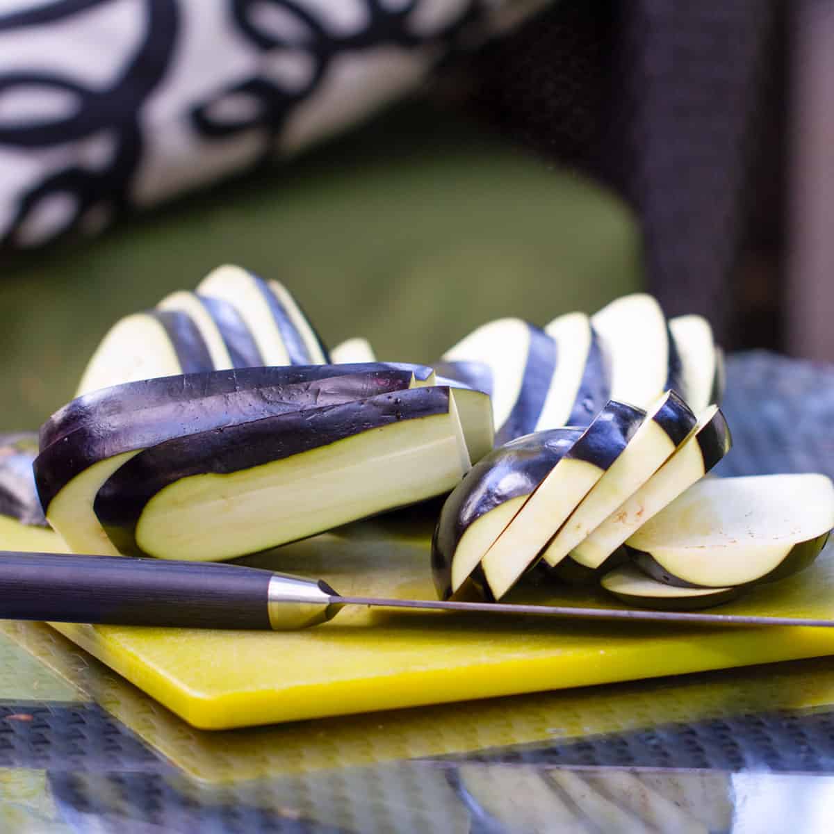 A whole eggplant worth of slices on a cutting board with knife