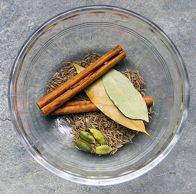 spices for biryani in a glass bowl. cinnamon stick, bay leaves, cumin seeds, cardamom pods