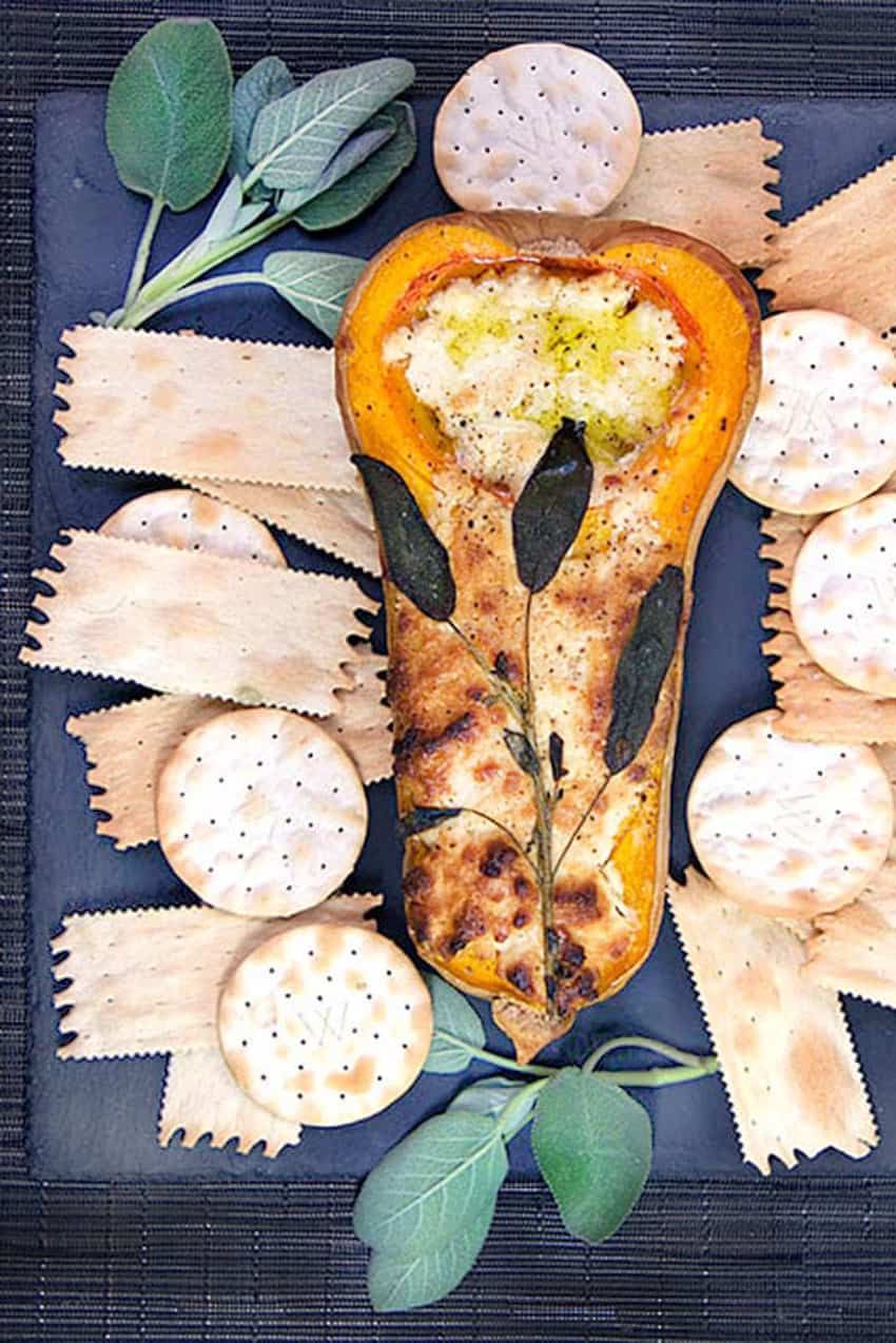 half a roasted butternut squash stuffed with blue cheese, topped with sage leaves and surrounded by crackers