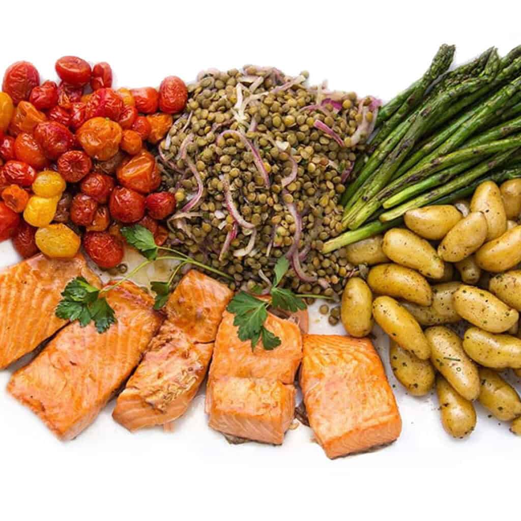 salmon nicoise on a platter: broiled salmon, fingerling potatoes, roasted tomatoes, asparagus and lentil salad.