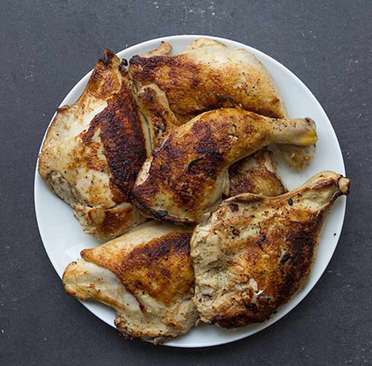 bone-in, skin-on chicken legs and breasts that have been browned and sit on a plate.