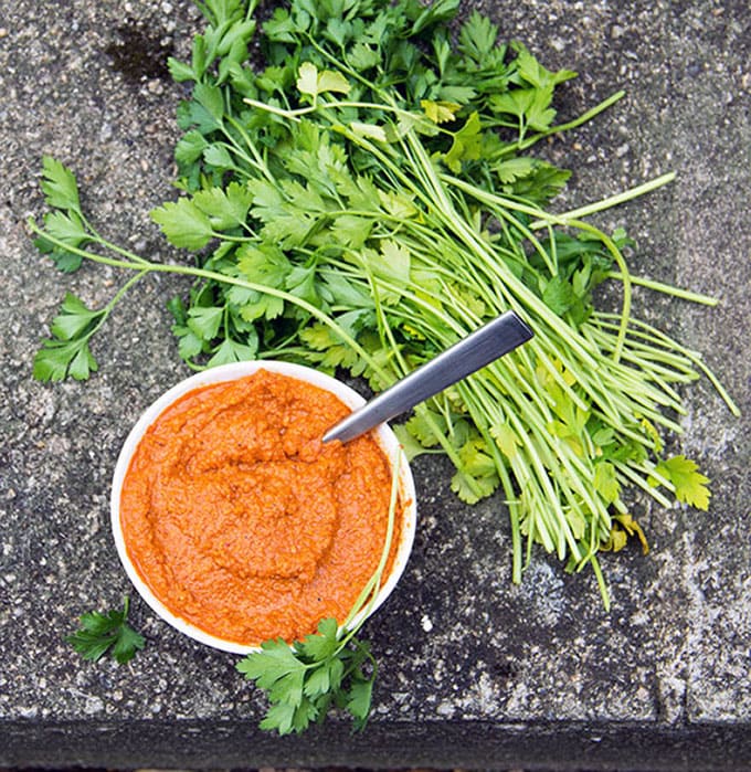 Spanish Romesco Sauce in a small bowl next to a big pile of parsley