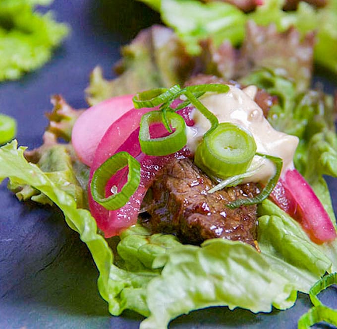 These Korean Beef Lettuce Wraps are an explosion of flavor. Famously delicious Korean Bulgogi beef wrapped up in lettuce leaves with homemade picked onions and radishes and miso mayonnaise. Serve as an appetizer or main dish l Panning The Globe Recipe