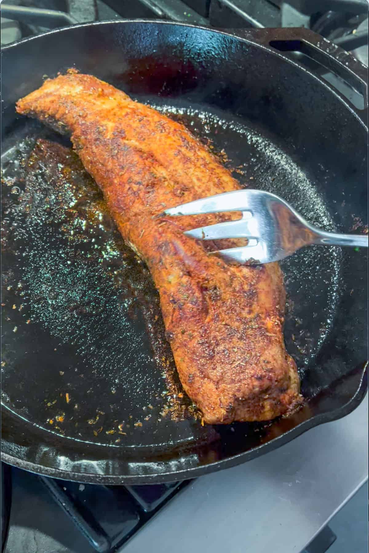 spiced crusted pork tenderloin searing in a cast iron skillet