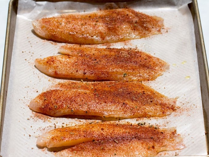 4 fish fillets coated with oil and blackening spices, set out on a wax paper lined baking sheet