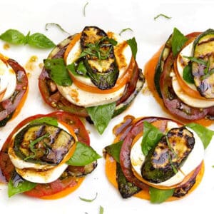 four caprese salad stacks with grilled zucchini and basil layered in.