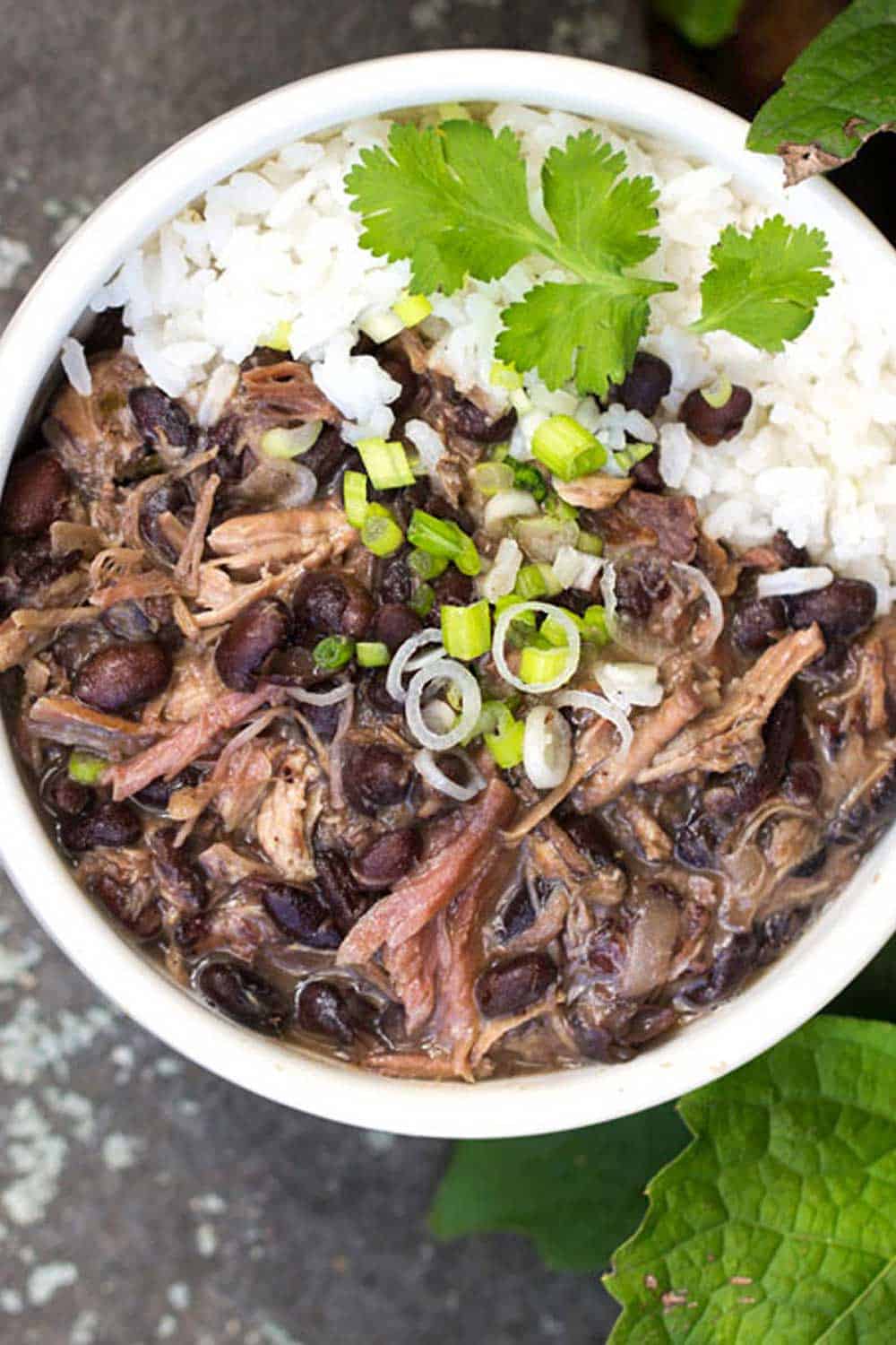 Slow cooker Brazilian Feijoada, Brazil's famous meat and bean stew, with rice, in a white bowl