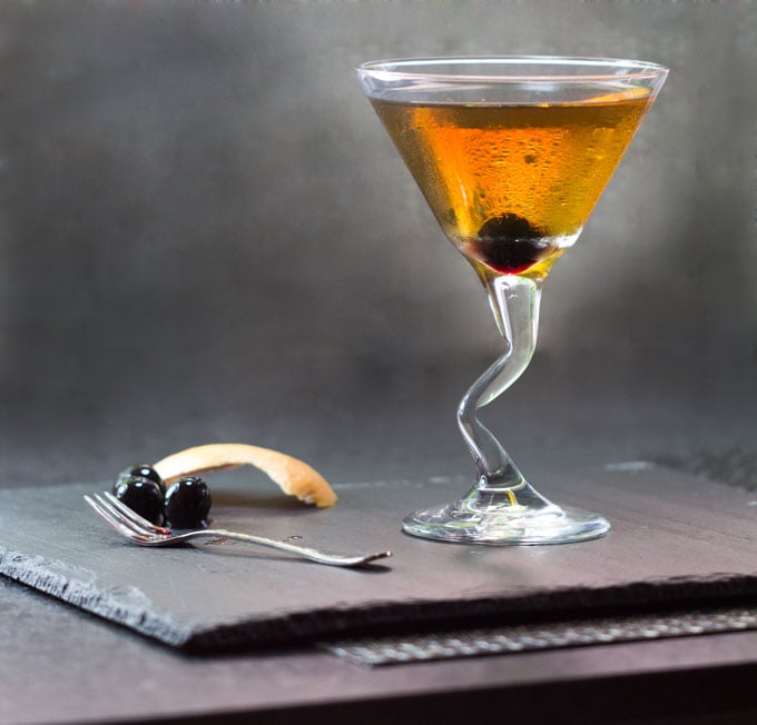 A Perfect Manhattan in a martini glass with Luxardo Cherries and a piece of grapefruit peel