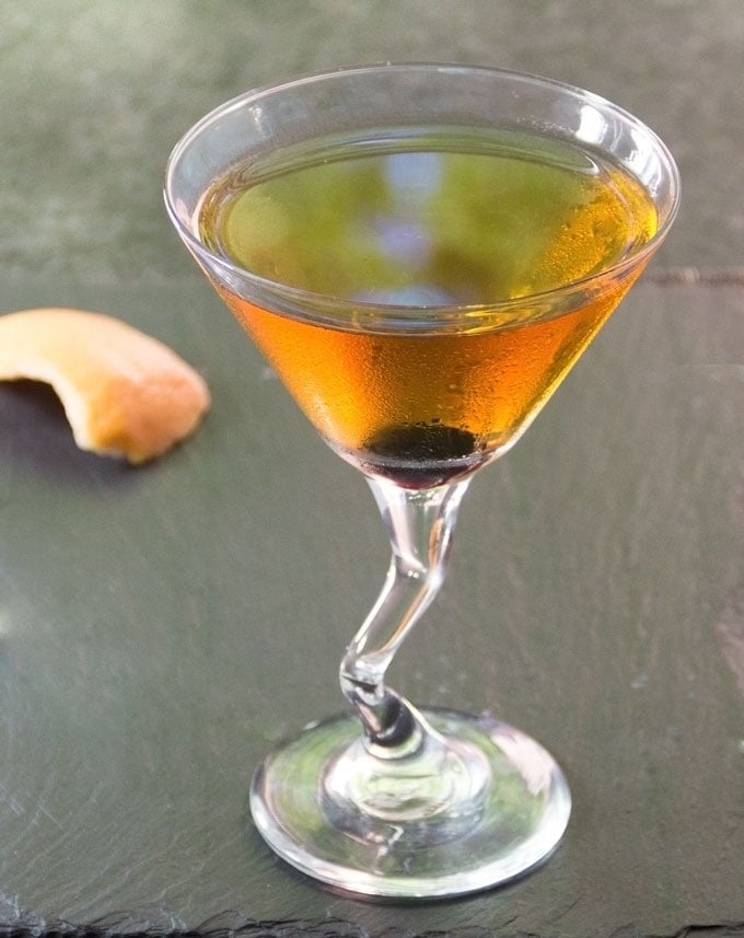 a perfect manhattan cocktail in a martini glass with a luxardo cherry at the bottom of the glass 