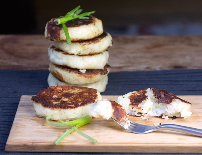 a stack of 5 potato patties plus one more on the cutting board and part of one that has been half eaten