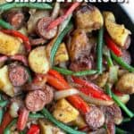 cast iron skillet filled with sautéd slices of sausage, chunks of potato, sliced red bell peppers and green beans