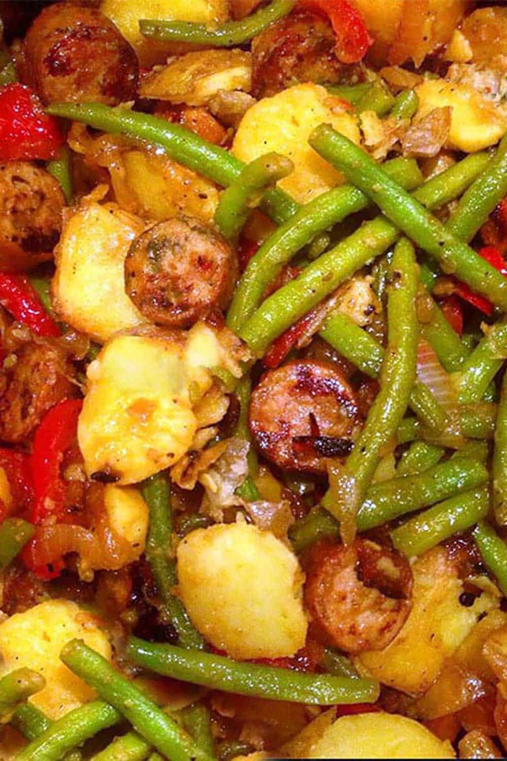 close up of sausages red peppers potatoes onions and green beans
