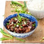 Asian honey soy chicken in a bowl sprinkled with scallions.