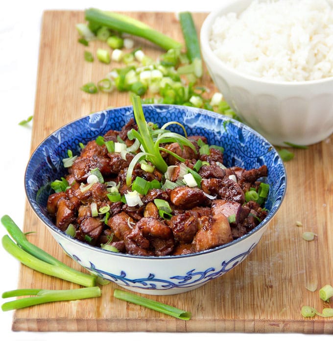 Asian honey soy chicken in a bowl sprinkled with scallions.