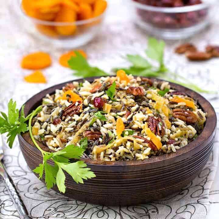 Wild rice salad with pecans, dried cranberries and apricots in a wooden serving bowl.