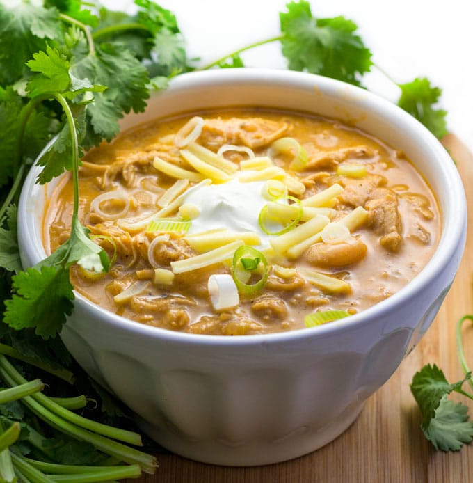 Bowl of white chicken chili with sour cream, cheese and scallions