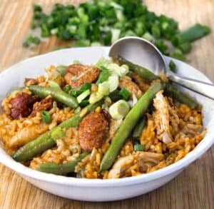 a bowl of spicy chicken jambalaya with sausages and green beans