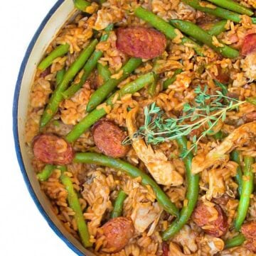 close up looking down into a white pot of spicy chicken jambalaya with sausages and green beans