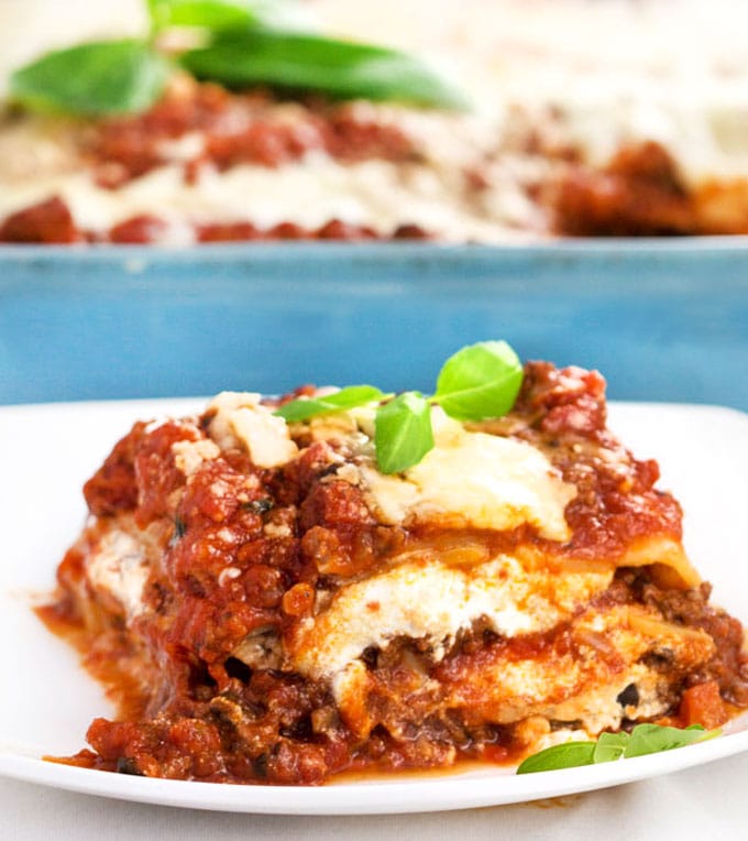 A close up shot of a square of meaty cheesy tomatoey lasagna on a plate