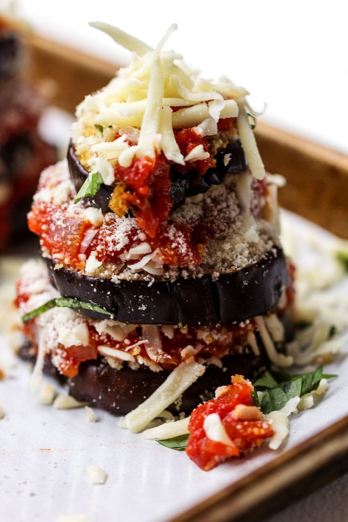 a stack of three eggplant rounds, layered with thick tomato sauce and shredded mozzarella cheese.