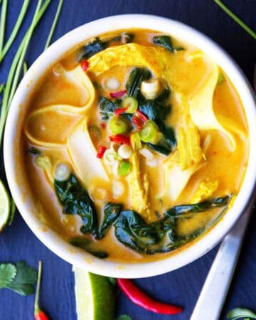 Thai coconut curry chicken soup with spinach and rice noodles, in a bowl
