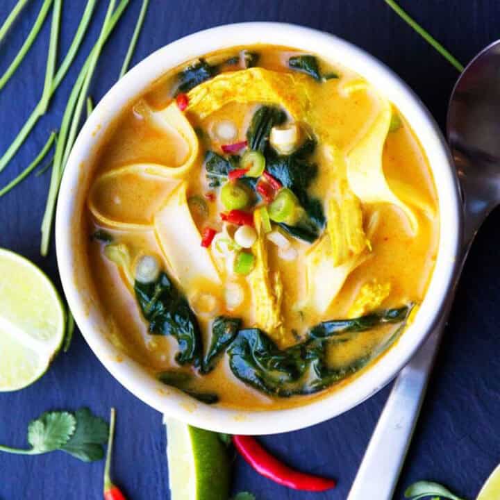 Thai coconut curry chicken soup with spinach and rice noodles, in a bowl