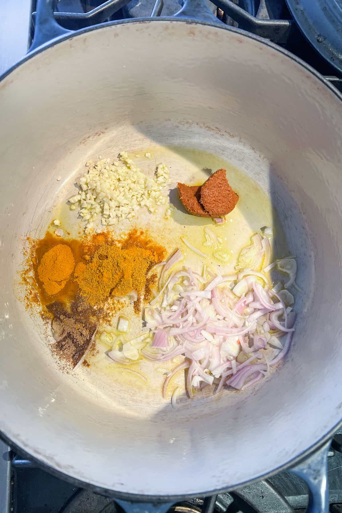 garlic, spices and shallots simmering in a pot.
