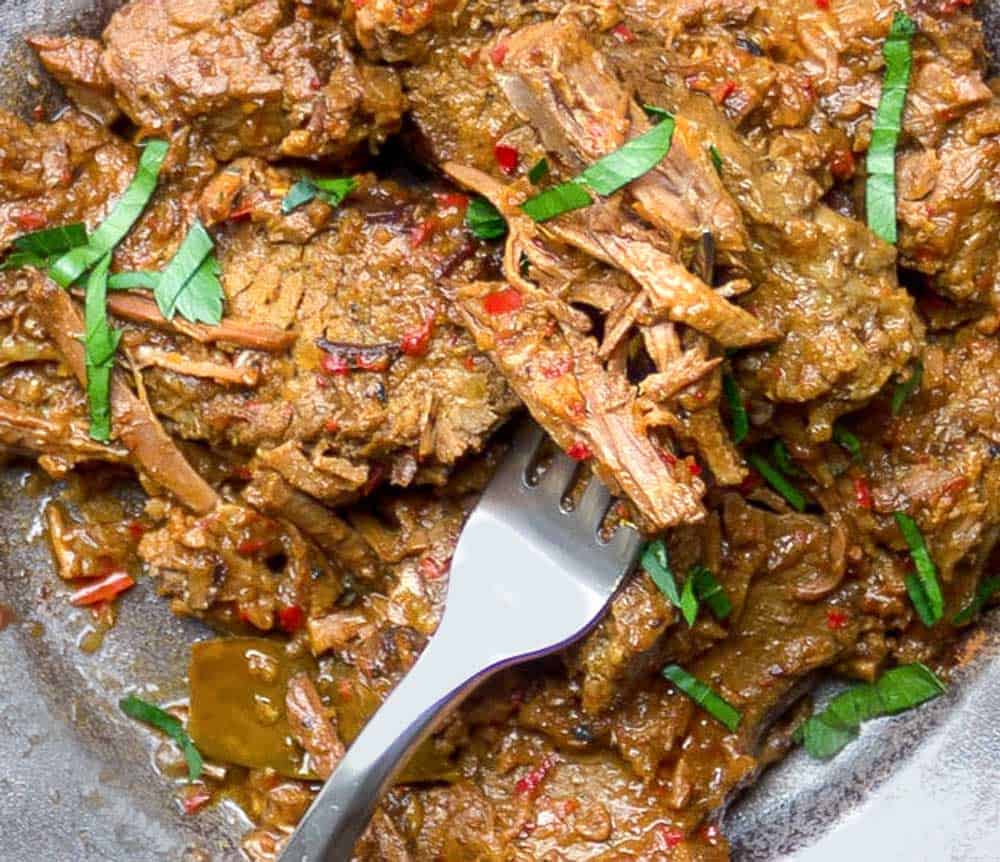 close up of shredded beef rendang brisket with a fork 