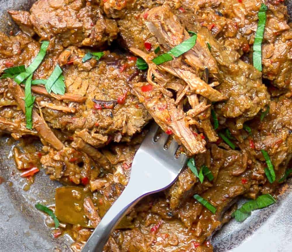 close up of shredded beef rendang brisket with a fork