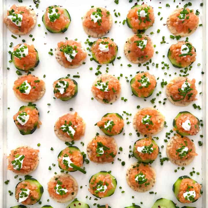 lots of smoked salmon tartare appetizers on a white wooden serving tray.
